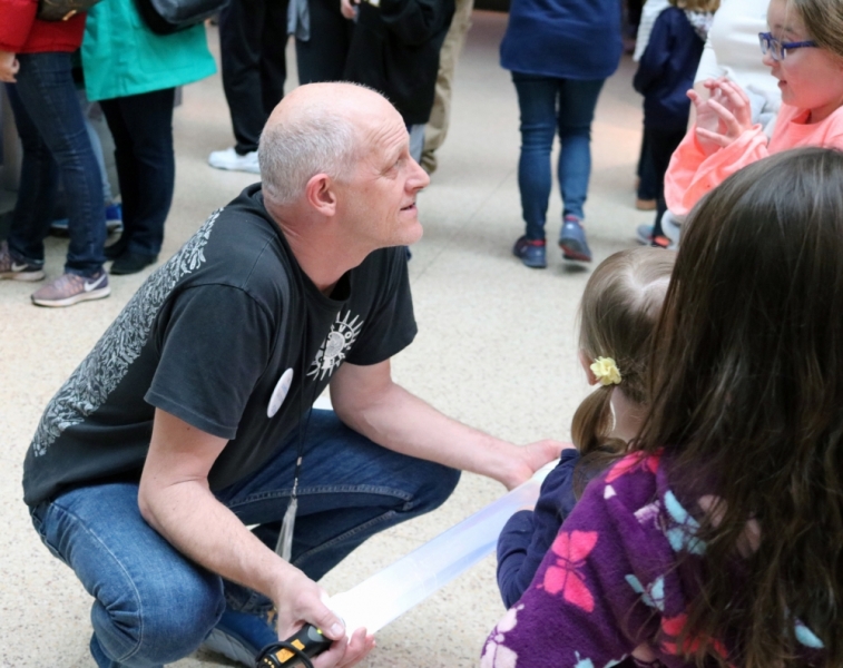 Allen Collins bends close to the ground where he talks to children about jellyfish.